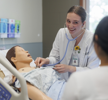 a health care professional working with a training manikin